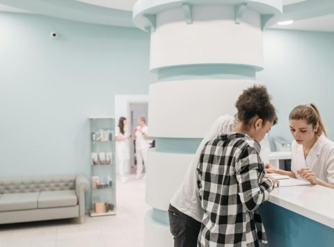 Healthcare professionals assisting at a modern clinic reception desk - Clinic software transition