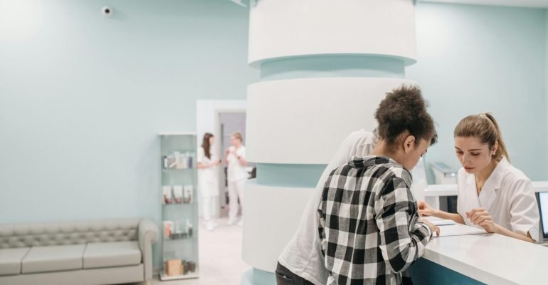 Healthcare professionals assisting at a modern clinic reception desk - Clinic software transition
