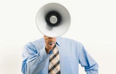 Businessman in blue shirt holding megaphone, symbolizing leadership and communication.