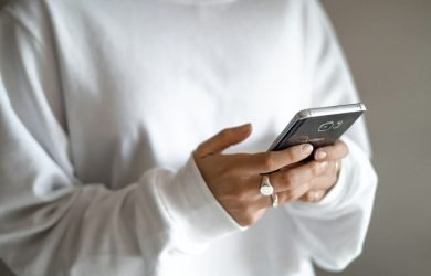 person in white long sleeve shirt holding black smartphone