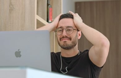 a man with glasses is looking at a laptop